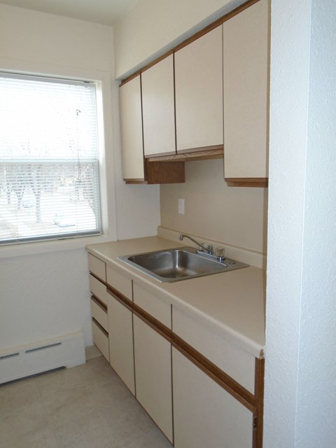 a kitchen with white cabinets and a sink and a window